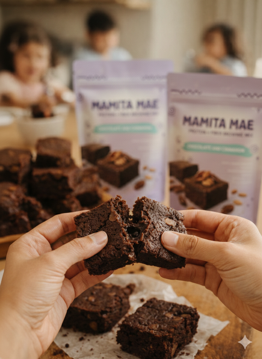 Hands breaking apart a fresh Mamita Mae brownie with product pouches in background